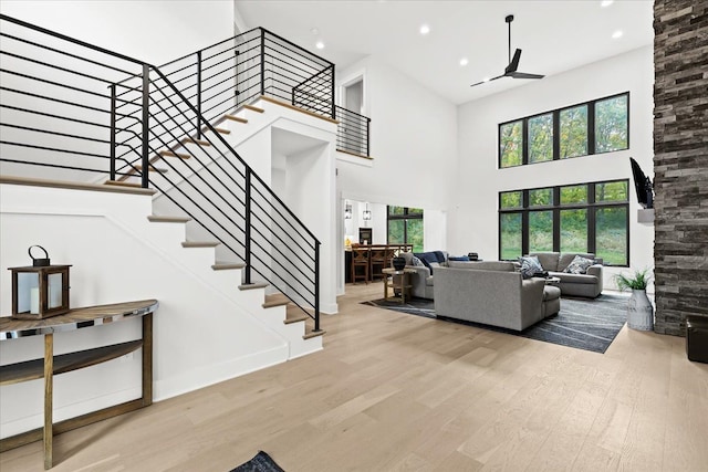 living room featuring stairs, recessed lighting, a high ceiling, and wood finished floors