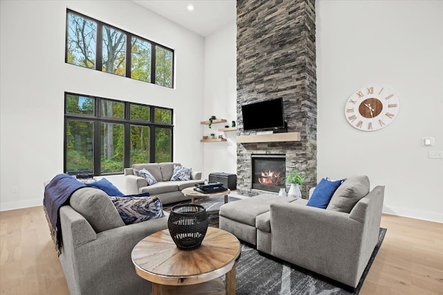 living area with baseboards, a fireplace, wood finished floors, and a towering ceiling