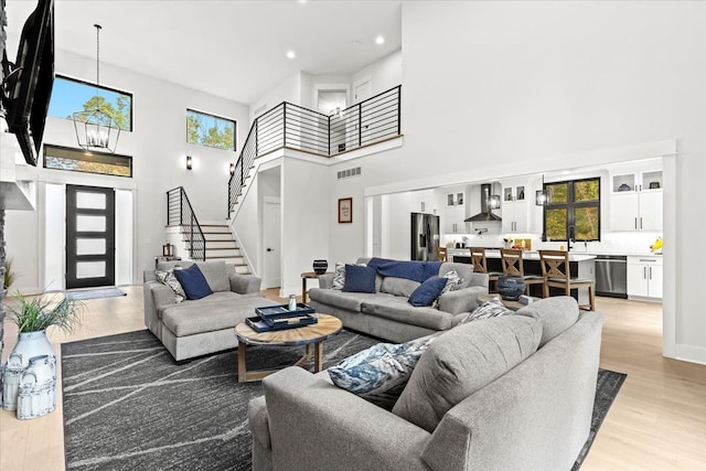 living area featuring a high ceiling, visible vents, and stairway