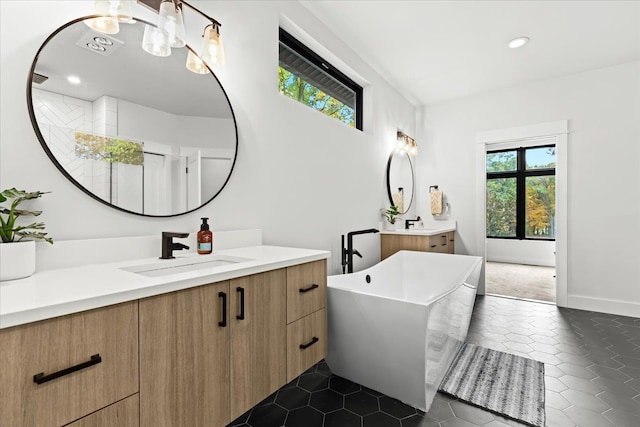 bathroom with a freestanding tub, tile patterned flooring, two vanities, a sink, and recessed lighting