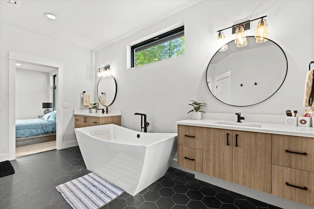 ensuite bathroom with ensuite bathroom, a sink, a freestanding bath, and two vanities