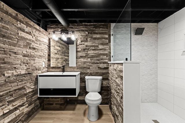 bathroom with a walk in shower, vanity, toilet, and wood finished floors