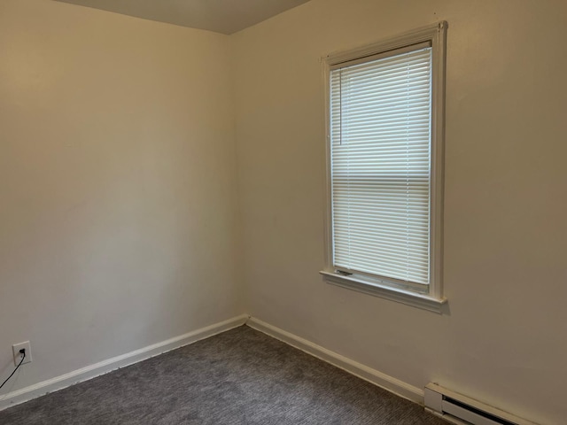 spare room featuring a baseboard radiator, baseboards, and dark colored carpet