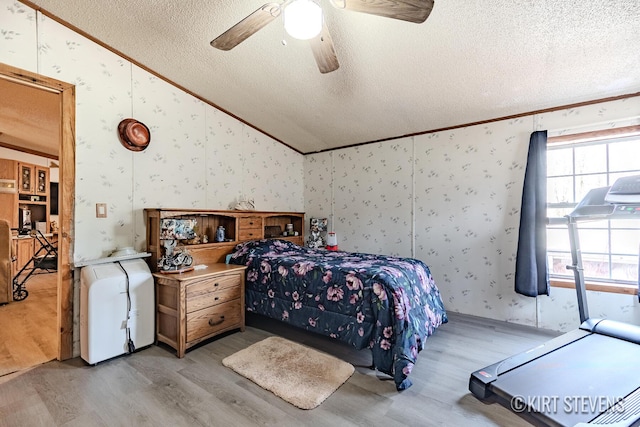 bedroom with crown molding, wallpapered walls, light wood-style flooring, and lofted ceiling