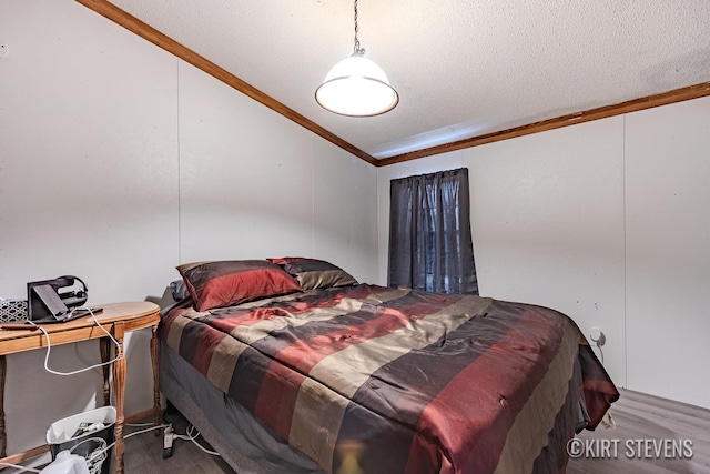 bedroom with a textured ceiling, ornamental molding, and wood finished floors