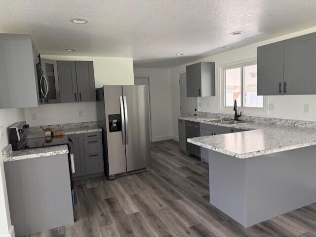 545 W Main St, Centreville, MI 49032 - kitchen featuring a sink, stainless steel appliances, a peninsula, gray cabinetry, and a textured ceiling