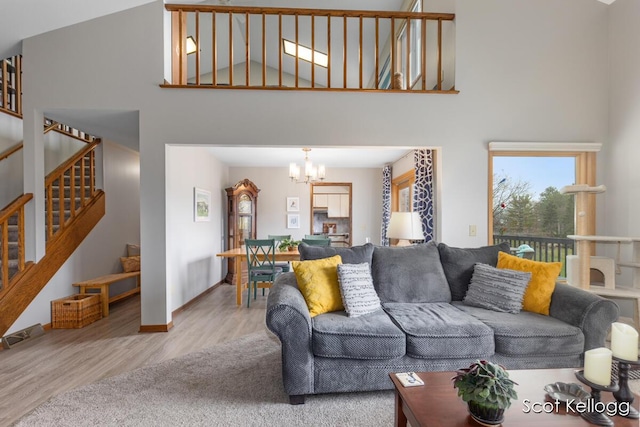 living area featuring a towering ceiling, wood finished floors, a notable chandelier, and stairs