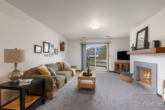 living room with a tiled fireplace and carpet floors