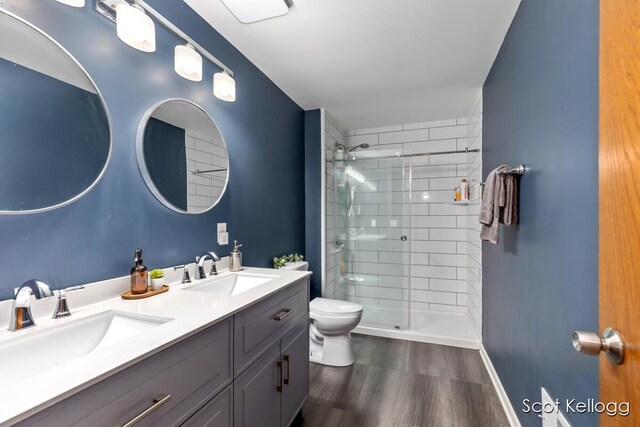 bathroom with a stall shower, toilet, wood finished floors, and a sink