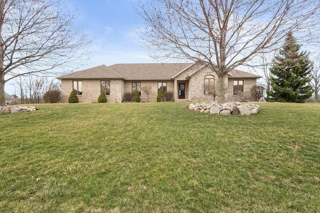ranch-style home with roof with shingles, brick siding, and a front lawn