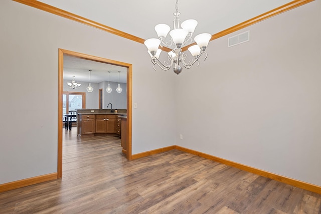 spare room with a chandelier, visible vents, dark wood finished floors, and baseboards