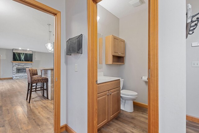 bathroom featuring baseboards, visible vents, wood finished floors, and toilet