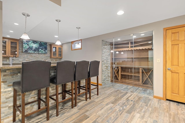 interior space featuring recessed lighting, wood finished floors, a bar, and pendant lighting
