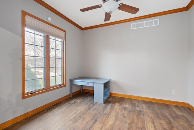 empty room featuring visible vents, plenty of natural light, crown molding, and baseboards