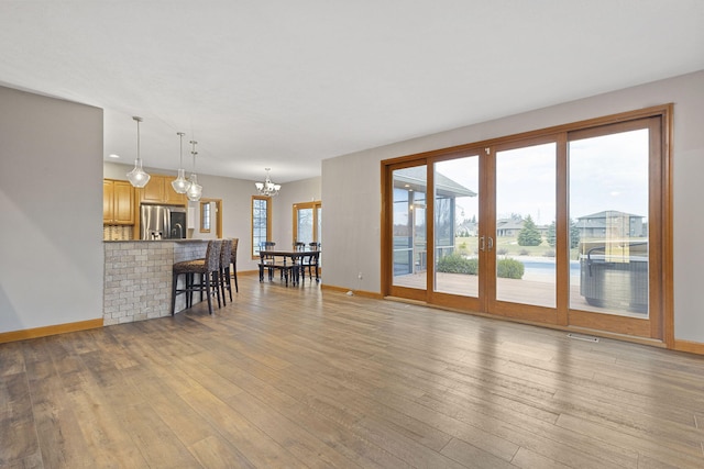 living area featuring an inviting chandelier, french doors, light wood finished floors, and baseboards