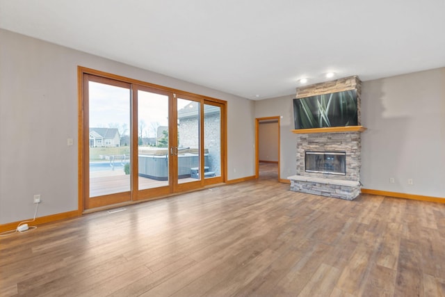 unfurnished living room featuring a fireplace, wood finished floors, and baseboards