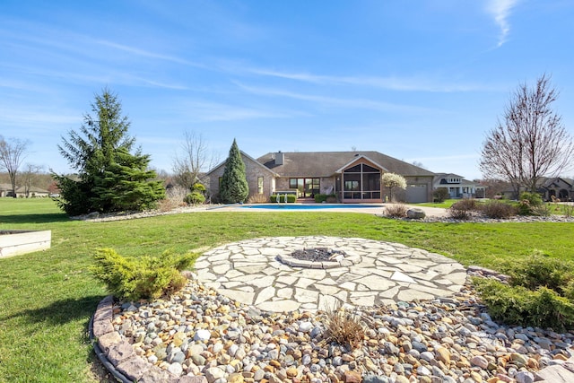 back of house featuring a lawn, a fire pit, a patio area, and an outdoor pool