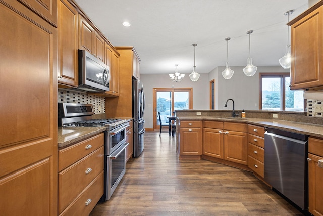 kitchen with tasteful backsplash, appliances with stainless steel finishes, brown cabinetry, and a sink