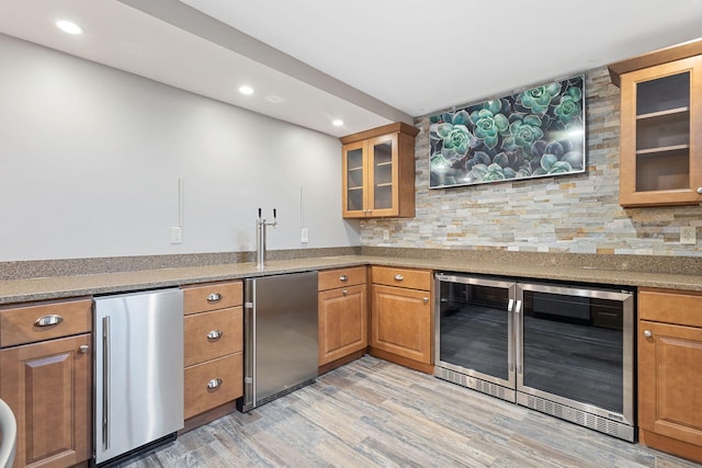 kitchen with beverage cooler, refrigerator, and brown cabinetry