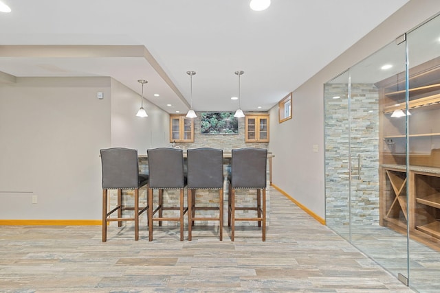 interior space featuring baseboards, recessed lighting, indoor bar, and light wood finished floors
