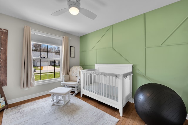 73941 Madison St, Armada, MI 48005 - bedroom featuring baseboards, ceiling fan, a nursery area, and wood finished floors