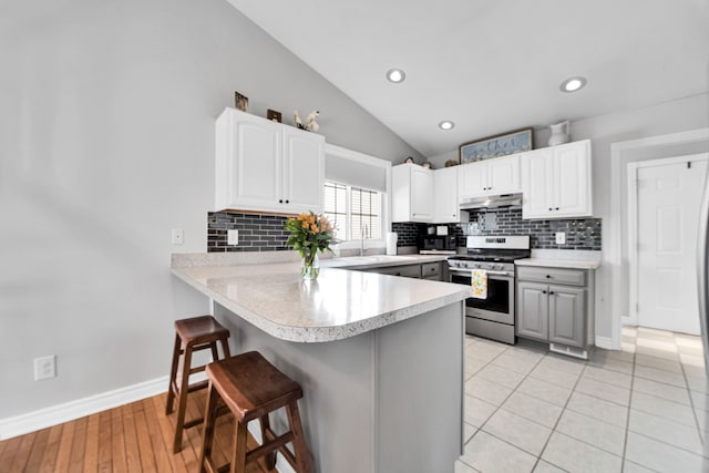 73941 Madison St, Armada, MI 48005 - kitchen with a breakfast bar area, backsplash, stainless steel gas stove, a peninsula, and under cabinet range hood