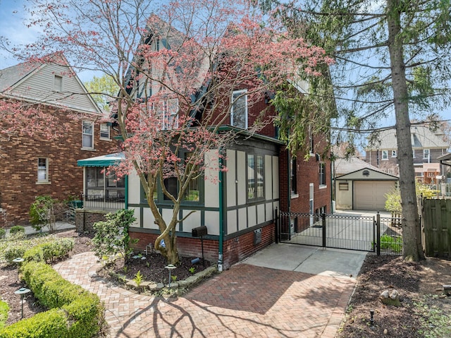 view of front of house with an outdoor structure, a gate, decorative driveway, fence, and a sunroom