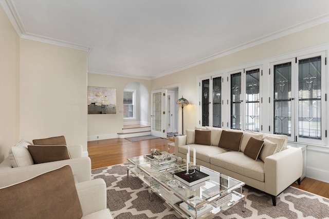 living room featuring crown molding, arched walkways, wood finished floors, and baseboards