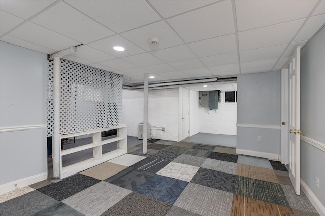 finished below grade area featuring recessed lighting, electric panel, and a drop ceiling