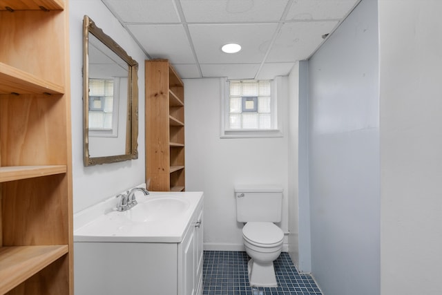 bathroom with toilet, vanity, a paneled ceiling, and tile patterned floors