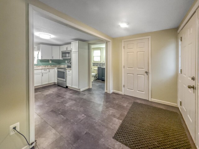 kitchen featuring light countertops, stainless steel appliances, white cabinets, and baseboards