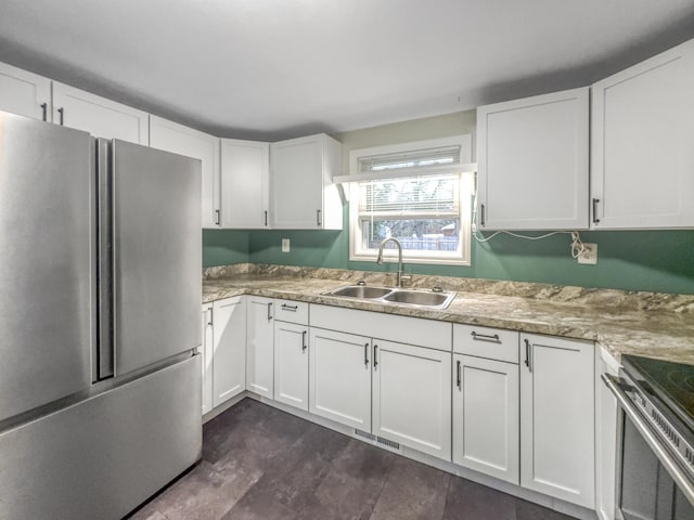 kitchen with a sink, stainless steel appliances, white cabinetry, and visible vents