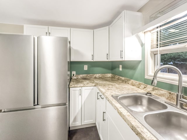 kitchen with freestanding refrigerator, a sink, white cabinets, and light countertops