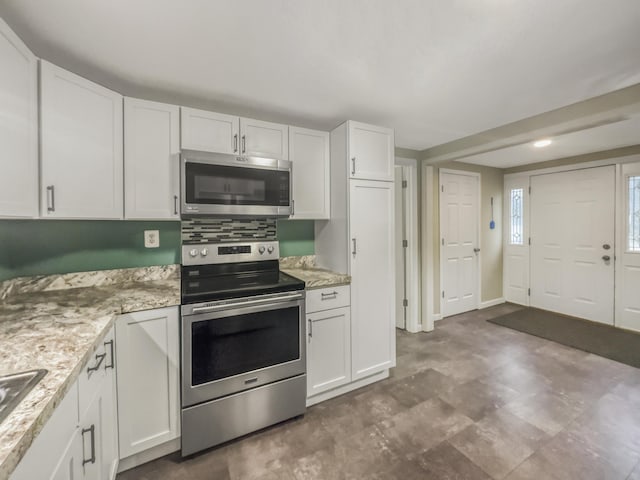 kitchen featuring light stone counters, white cabinets, and stainless steel appliances