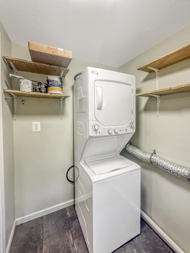 washroom featuring laundry area, baseboards, stacked washing maching and dryer, and dark wood finished floors
