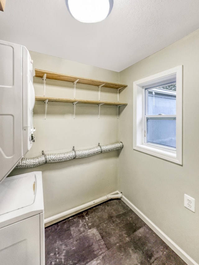 clothes washing area with laundry area, baseboards, and stacked washing maching and dryer