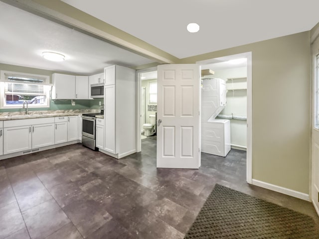 kitchen with baseboards, light countertops, white cabinetry, a sink, and stainless steel appliances