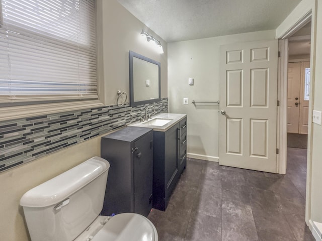 bathroom featuring a textured ceiling, tasteful backsplash, vanity, baseboards, and toilet