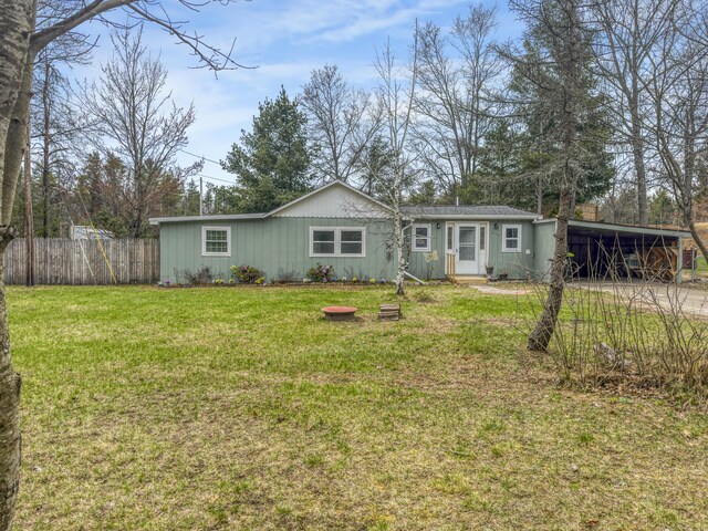 manufactured / mobile home with fence, a front lawn, board and batten siding, an attached carport, and driveway