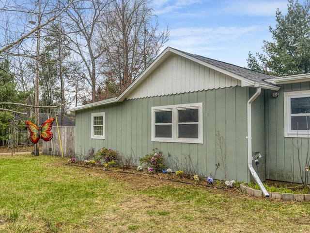 view of home's exterior with a lawn, board and batten siding, and fence