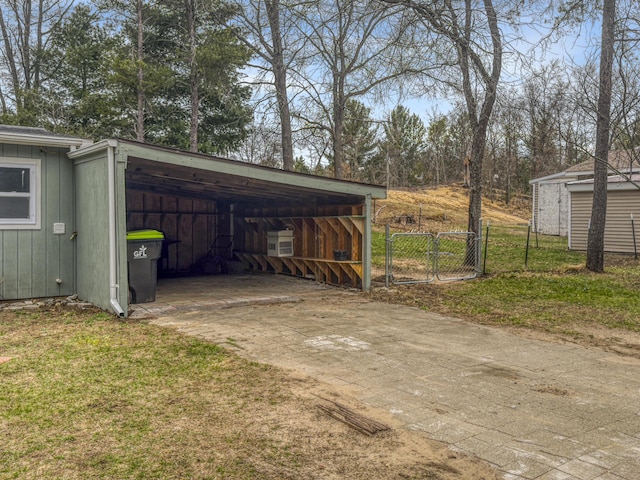 exterior space featuring an outbuilding, a gate, a carport, fence, and concrete driveway