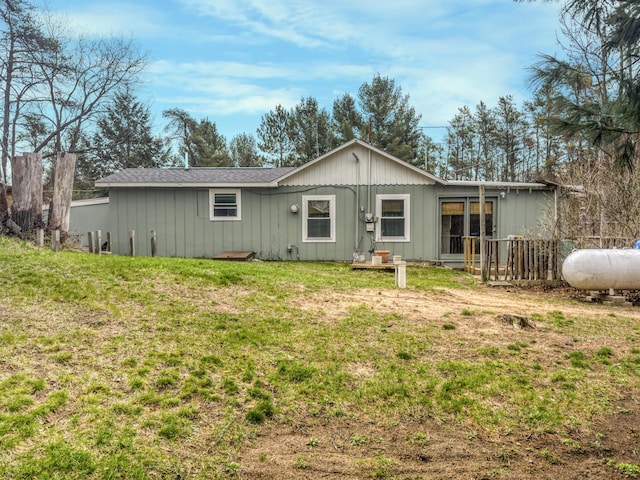 rear view of property featuring a lawn, board and batten siding, and fence