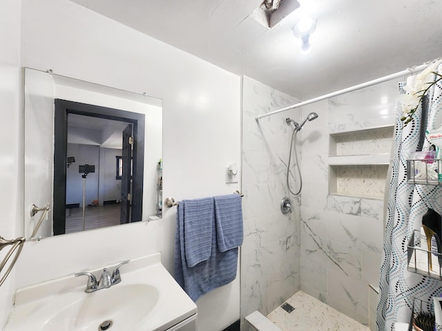 bathroom featuring a tile shower and vanity
