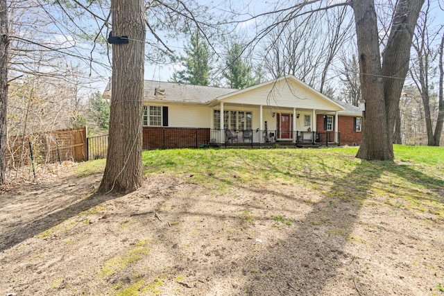 ranch-style home featuring covered porch, brick siding, fence, and a shingled roof