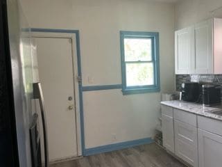 3015 Van Dyke St, Detroit, MI 48214 - interior space featuring baseboards, tasteful backsplash, wood finished floors, and light stone counters