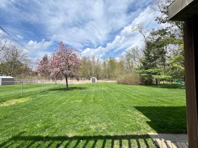 view of yard featuring a storage shed, fence, and an outbuilding