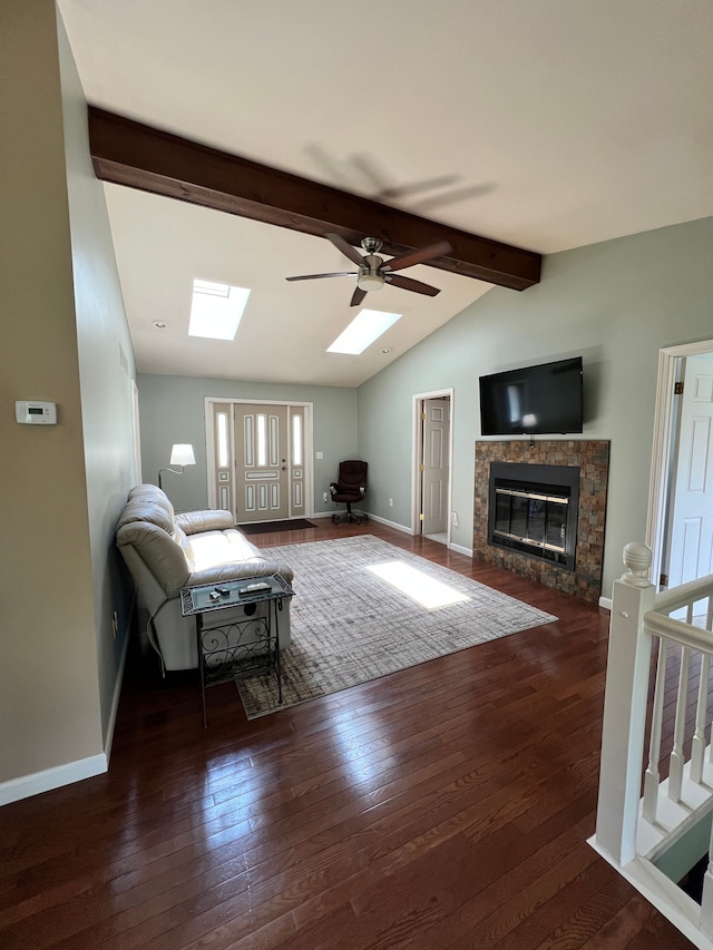 living room with ceiling fan, hardwood / wood-style flooring, a glass covered fireplace, baseboards, and lofted ceiling with skylight