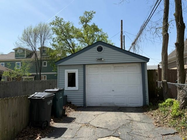 detached garage featuring aphalt driveway and fence