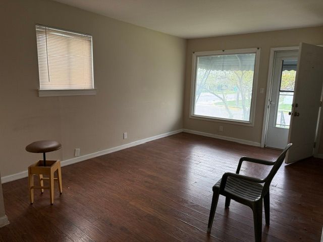 unfurnished room with baseboards and dark wood-type flooring