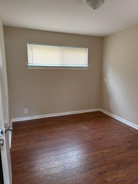 empty room featuring baseboards and dark wood-style flooring